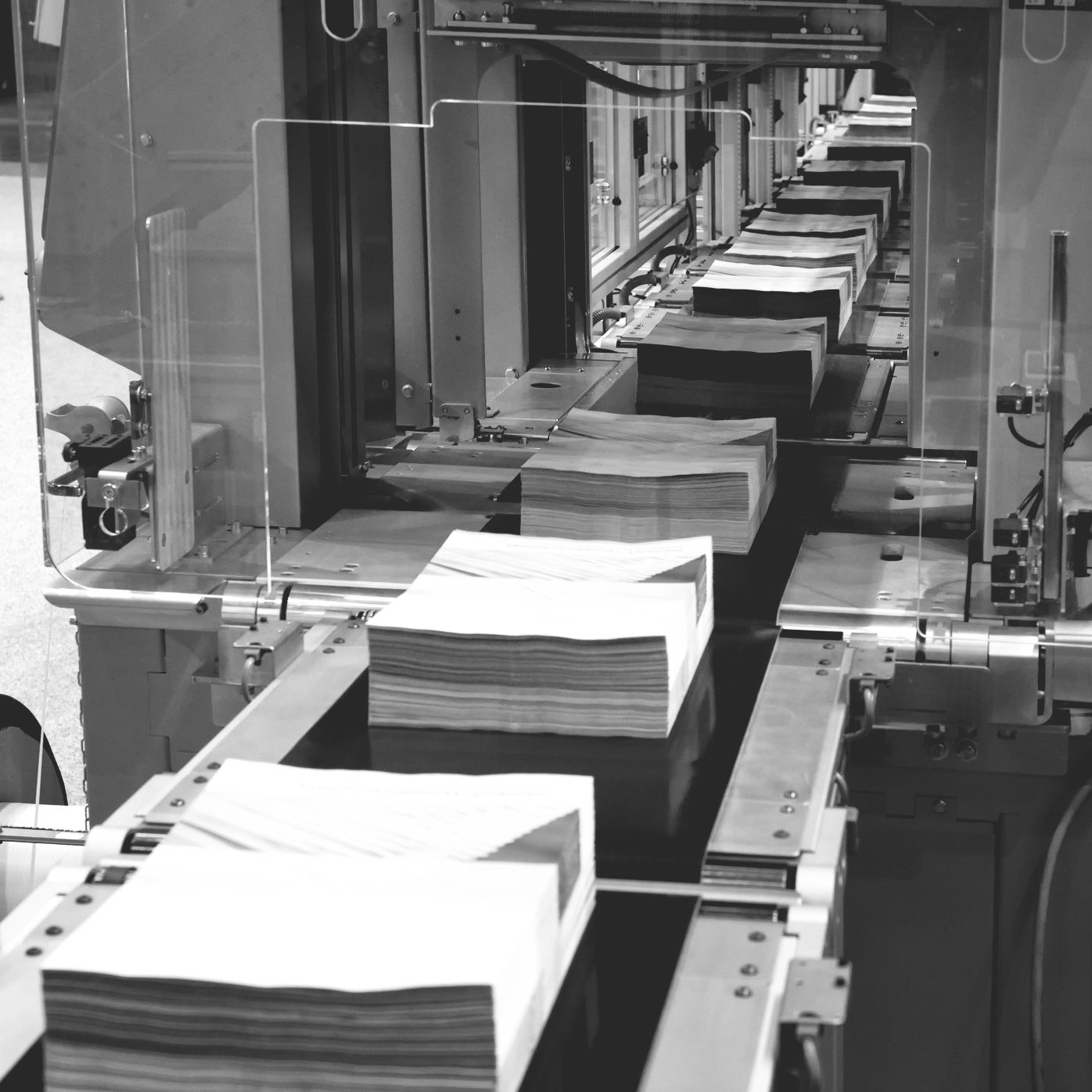Conveyor belt with stacks of pages on it in black and white